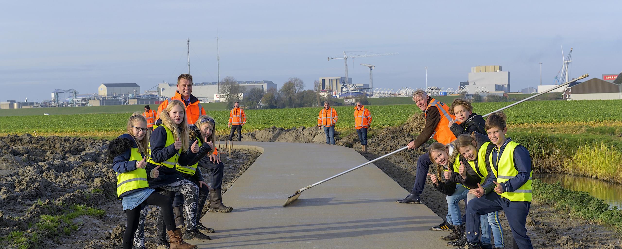 Wethouder Harry Boon, de nieuwe CEO van Koninklijke Oosterhof Holman en kinderen uit de basisschool van Midlumbewonderen het eerste deel van het nieuwe fietspad Wijnaldum - Midlum