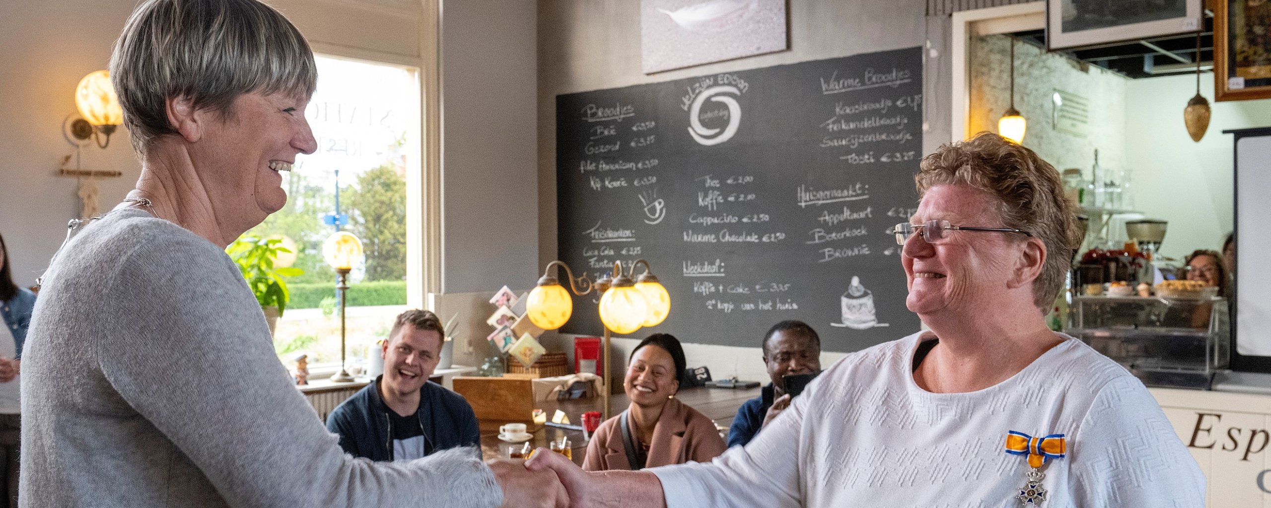 Burgemeester Ina Sjerps die de koninklijke onderscheiding bij mevrouw Liefting opspeld.