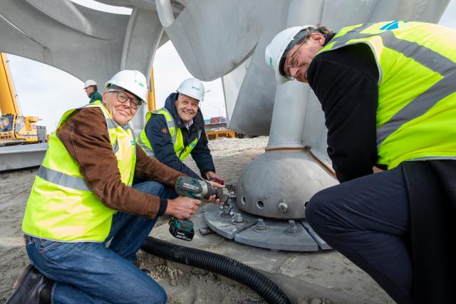 Wethouders Harry Boon, Erik de Groot en Paul Scholte verankeren het kunstwerk met het aandraaien van de bouten.
